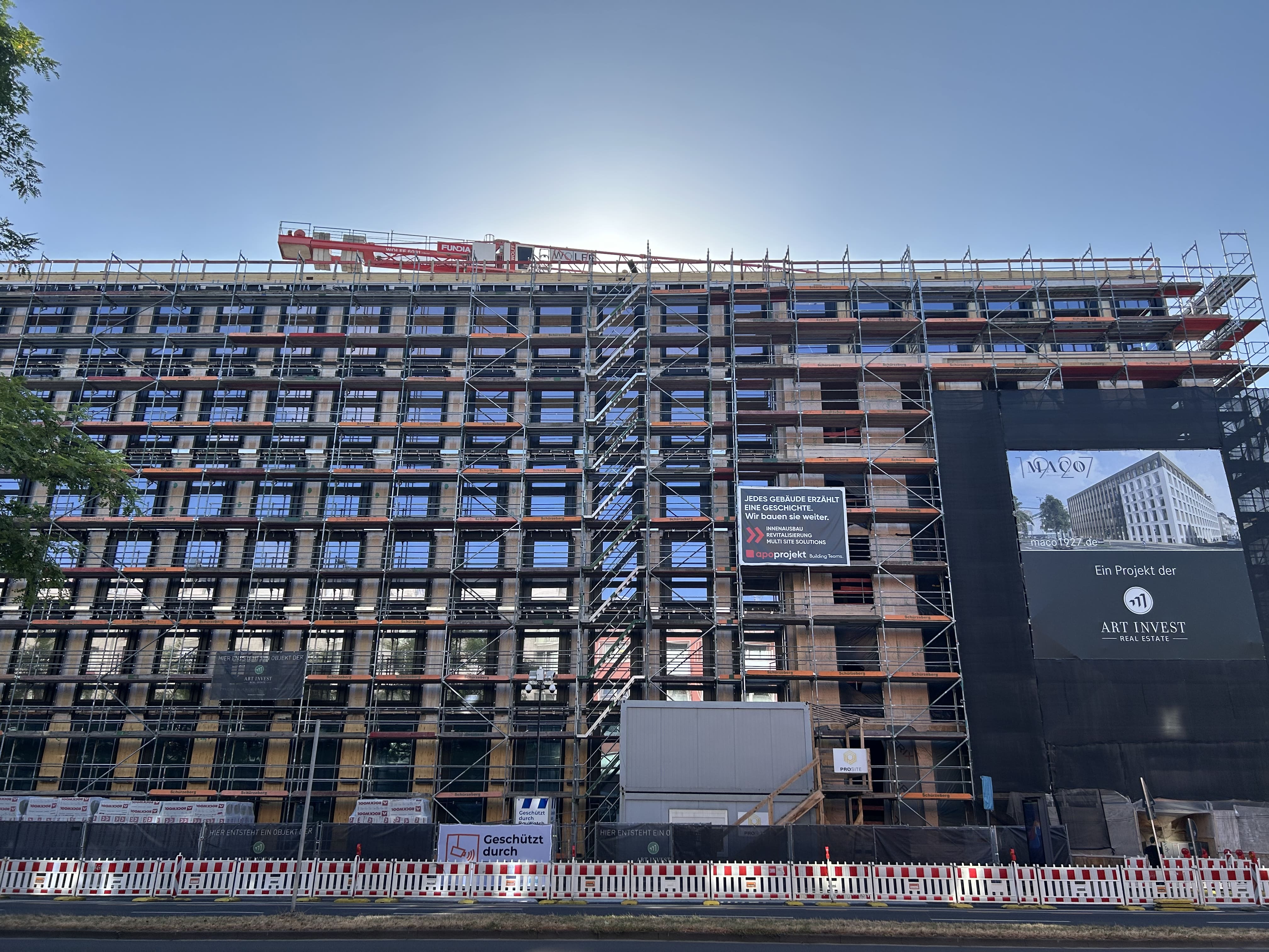 Außenansicht des MACO-Bauvorhabens in Köln mit Baugerüst und Projektbanner von Art-Invest Real Estate